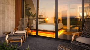 A modern bedroom with a glass door, a bed, and a seating area with chairs and a table. - ViewPoint Hotel (York Beach)