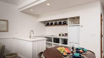 A modern kitchen with white cabinetry, a built-in microwave, and a dining area with a round table set for four.