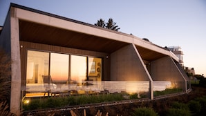 A modern house with a glass facade, outdoor seating, and a view of the sea. - ViewPoint Hotel (York Beach)