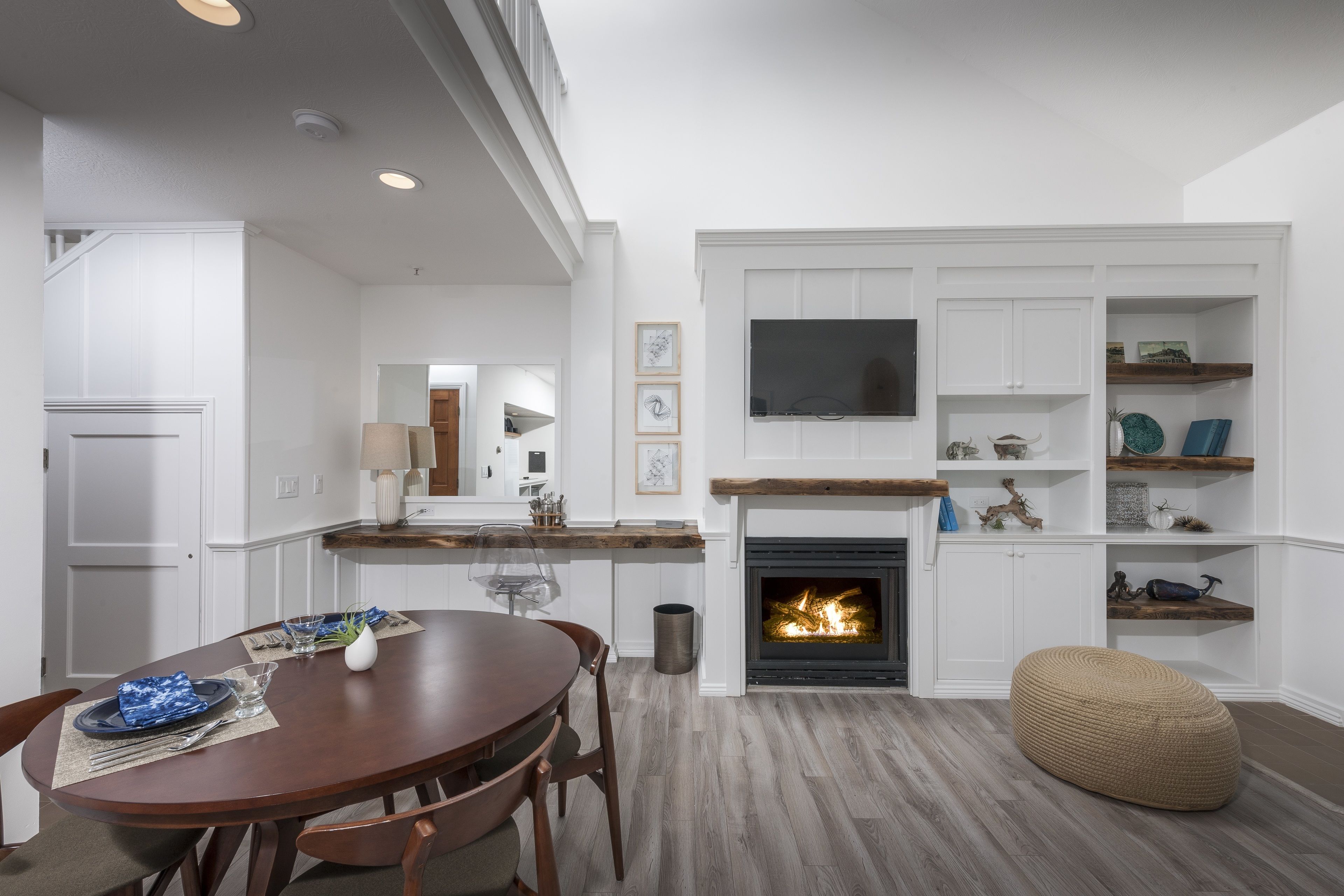 A modern kitchen with white cabinetry, a built-in TV, and a fireplace.