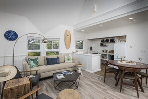 A modern living room with a sofa, coffee table, and dining area with chairs.