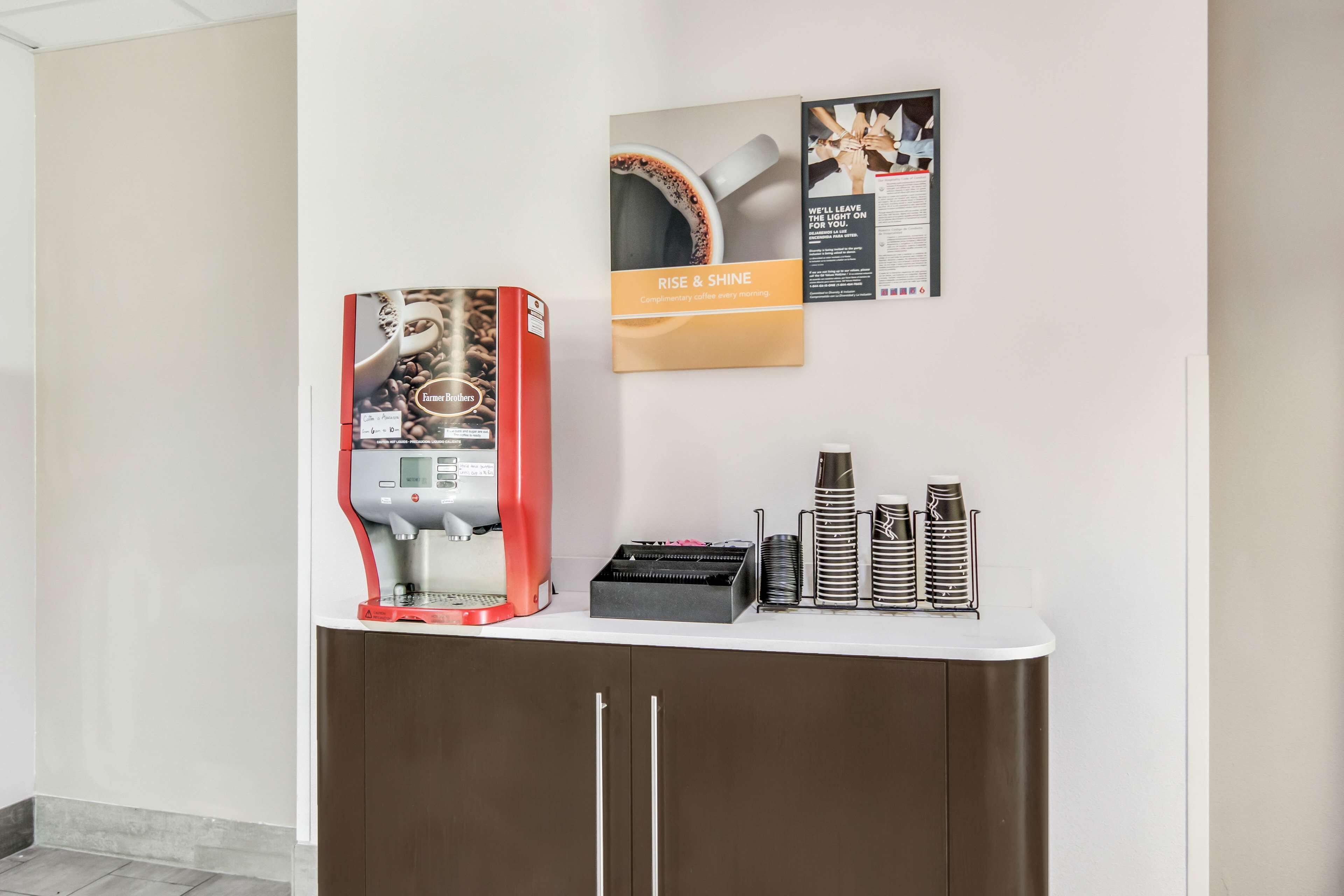 Un angolo caffè con una macchina per il caffè, tazze e un menu appeso al muro.