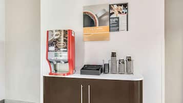 Un angolo caffè con una macchina per il caffè, tazze e un menu appeso al muro.