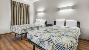 Habitación de hotel con dos camas, piso de madera y una ventana con cortinas.
