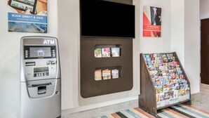 Un cajero automático, un panel informativo en la pared y un expositor con folletos.