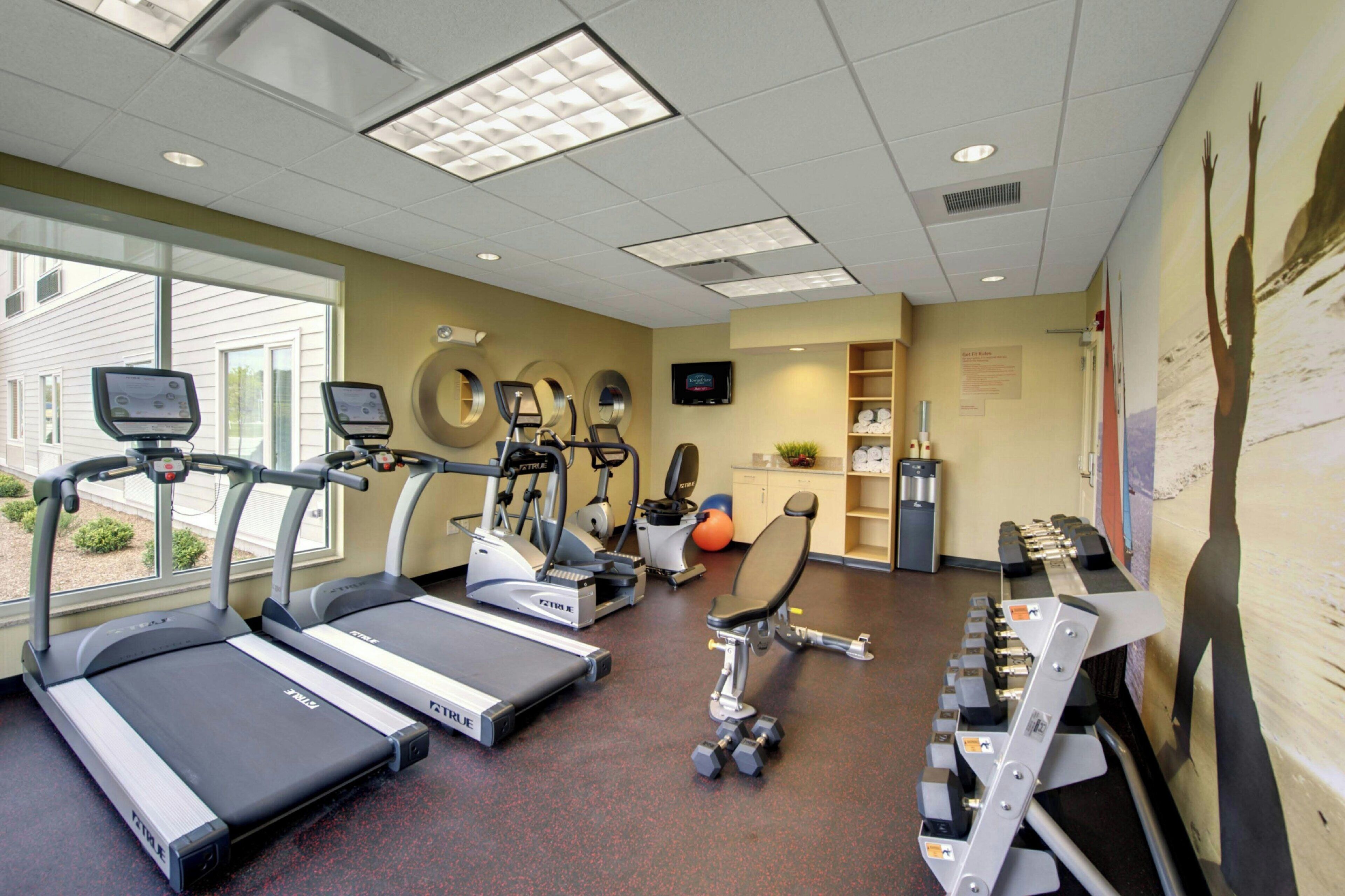 A fitness center with treadmills, elliptical machines, and weight benches.