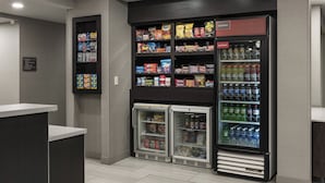 A self-service snack and beverage area with refrigerated and non-refrigerated shelves stocked with various snacks and drinks.