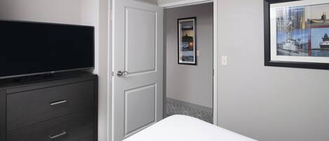 A bedroom with a bed, a dresser, a television, and a framed picture on the wall.
