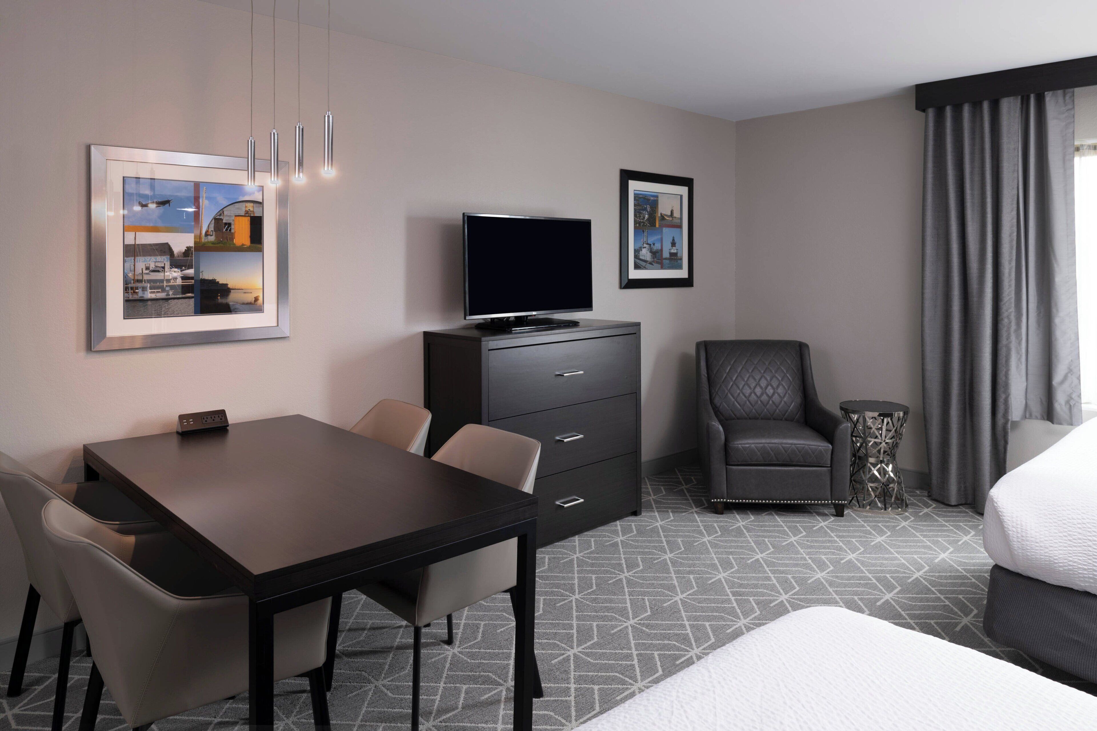 A hotel room with a bed, a TV, a desk, and chairs.