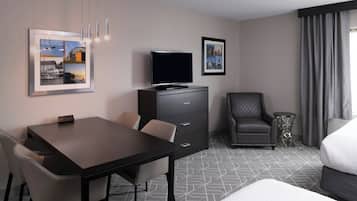 A hotel room with a bed, a TV, a desk, and chairs.