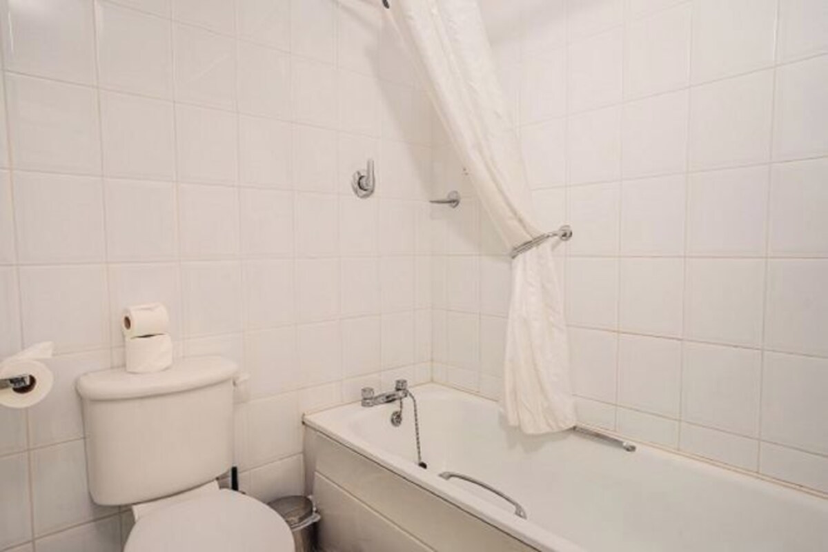 A bathroom with a toilet, a bathtub, and a shower curtain.