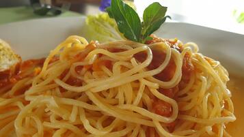 A plate of spaghetti with tomato sauce and a basil leaf garnish.