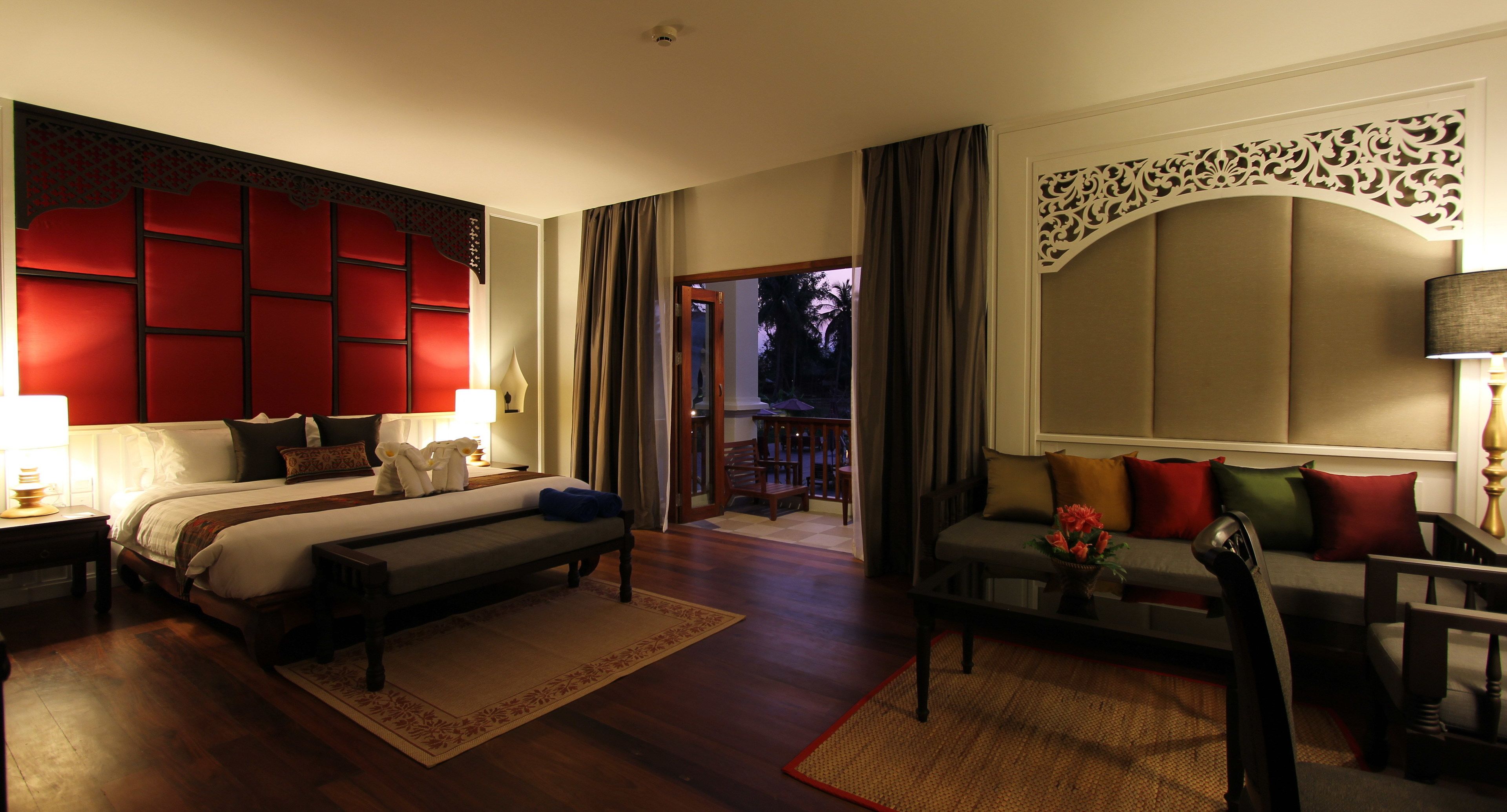 A hotel room with a large bed, a sofa, a desk, and a view of the outdoors.
