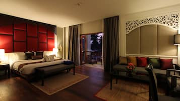 A hotel room with a large bed, a sofa, a desk, and a view of the outdoors.