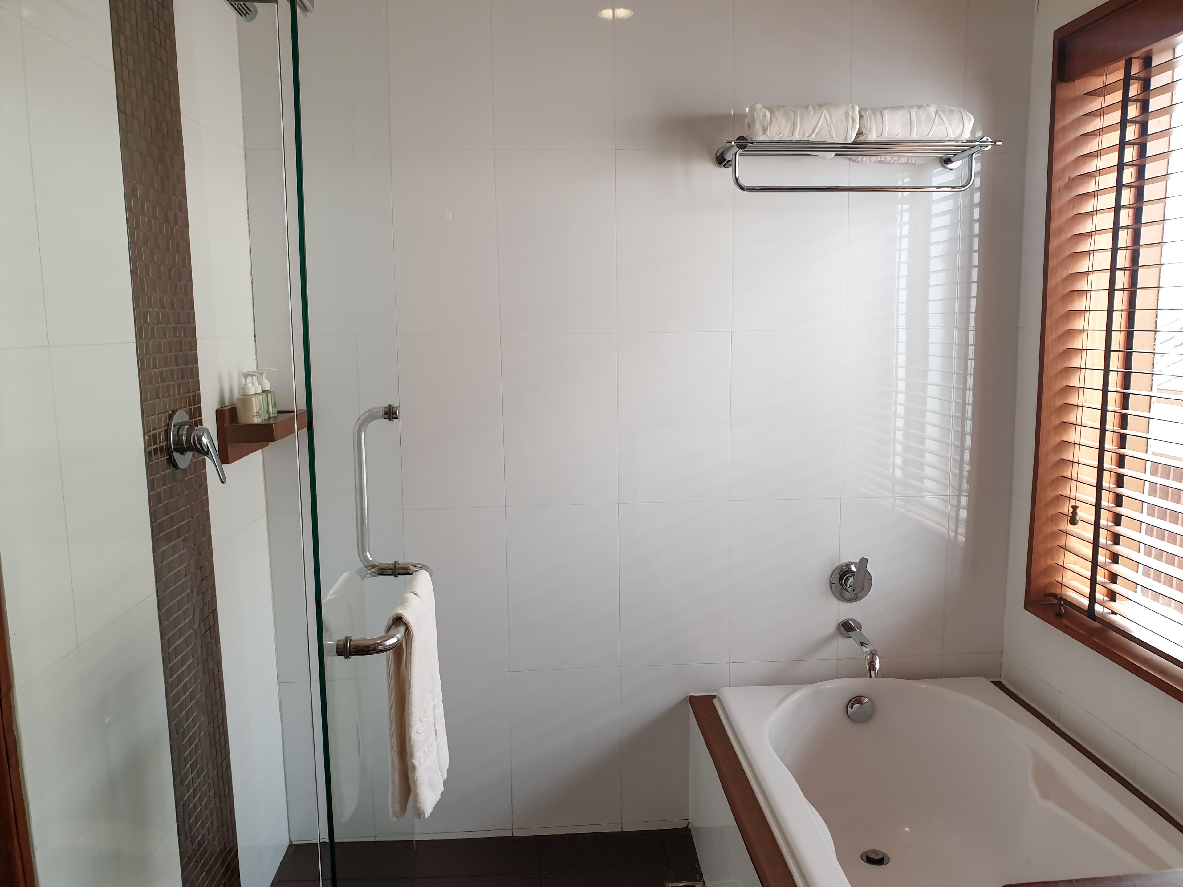 Une salle de bain moderne avec une douche à l’italienne, une baignoire et un porte-serviettes.
