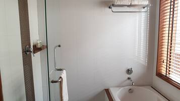 Une salle de bain moderne avec une douche à l’italienne, une baignoire et un porte-serviettes.