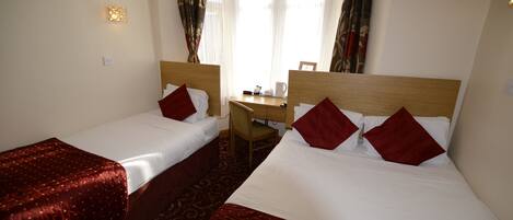 A hotel room with two single beds, a desk, and a chair.