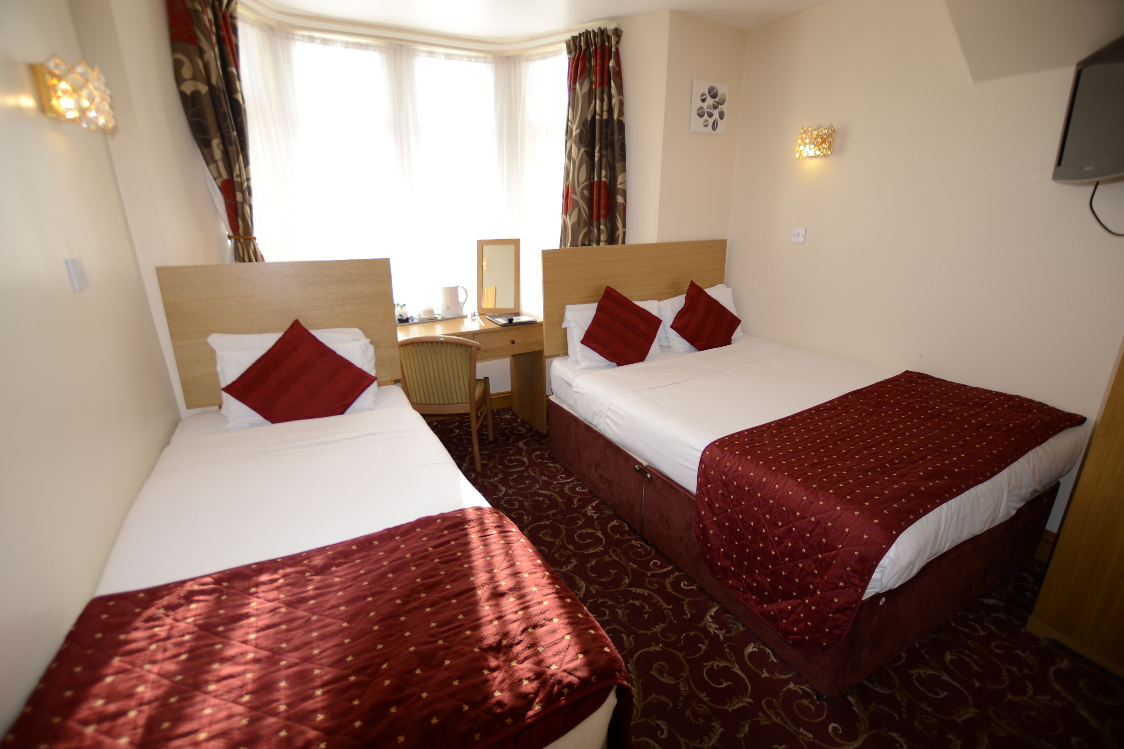 A hotel room with two beds, a desk, and a television.