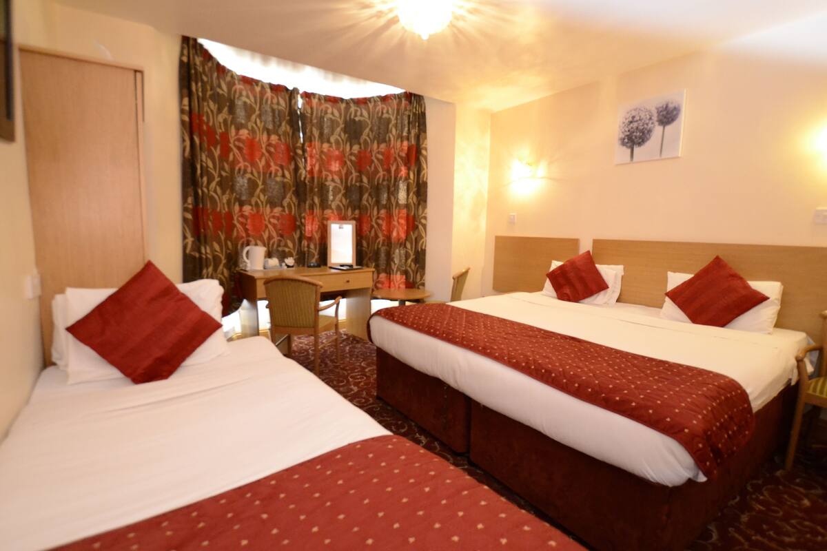 Habitación de hotel con dos camas, un escritorio y una silla.