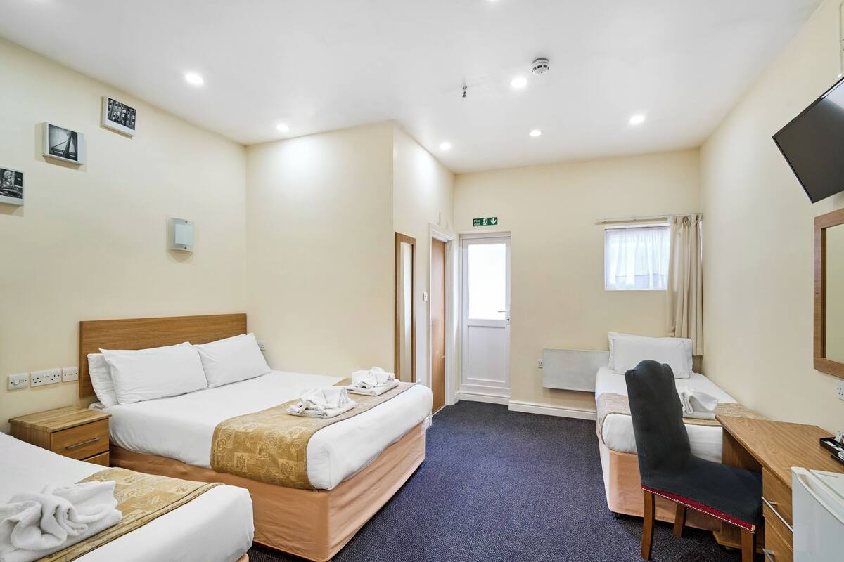 Una habitación de hotel con cama, escritorio, silla, televisor y puerta al baño.
