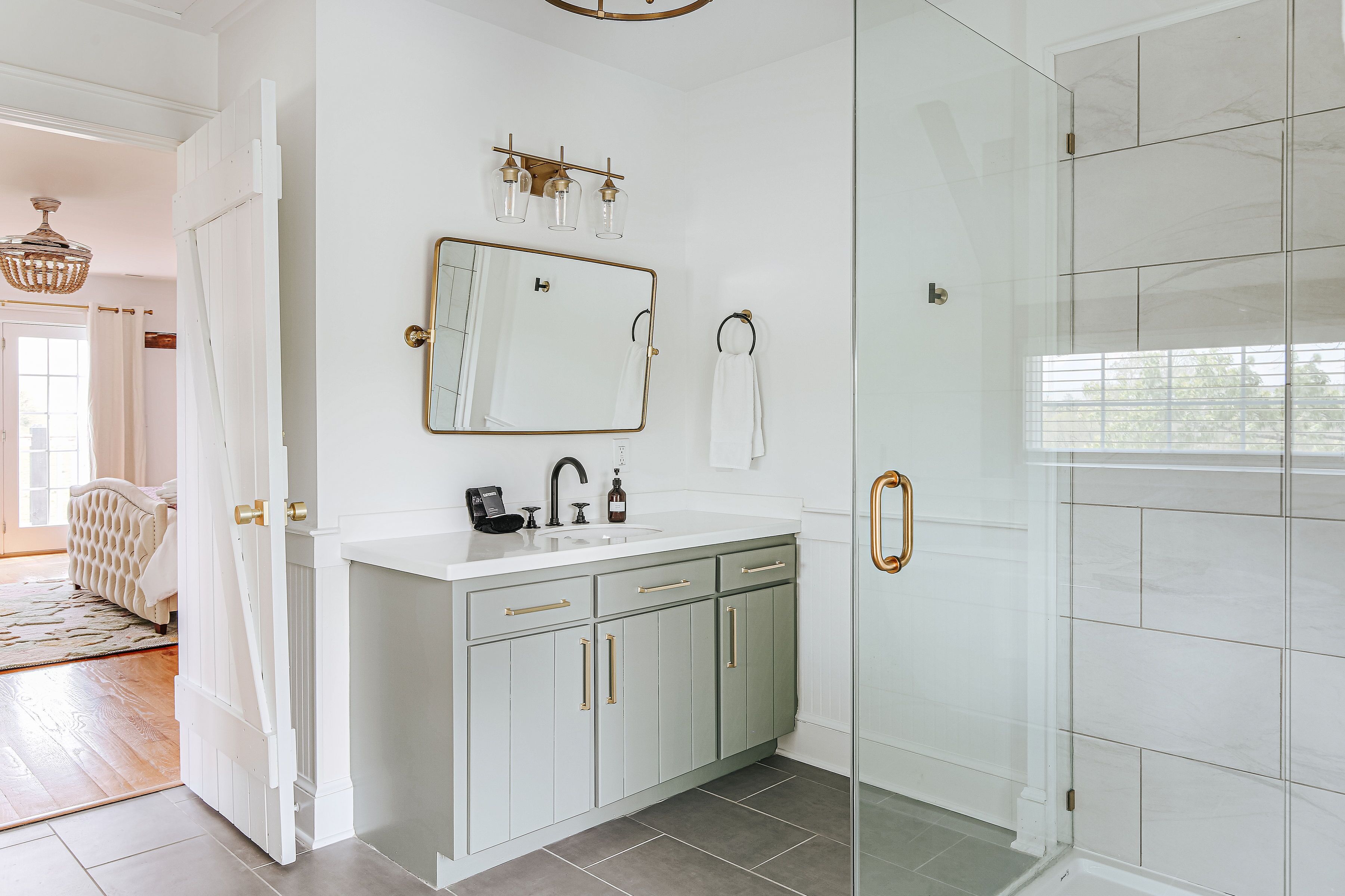 A bathroom with a white vanity, a large mirror, and a glass shower enclosure.