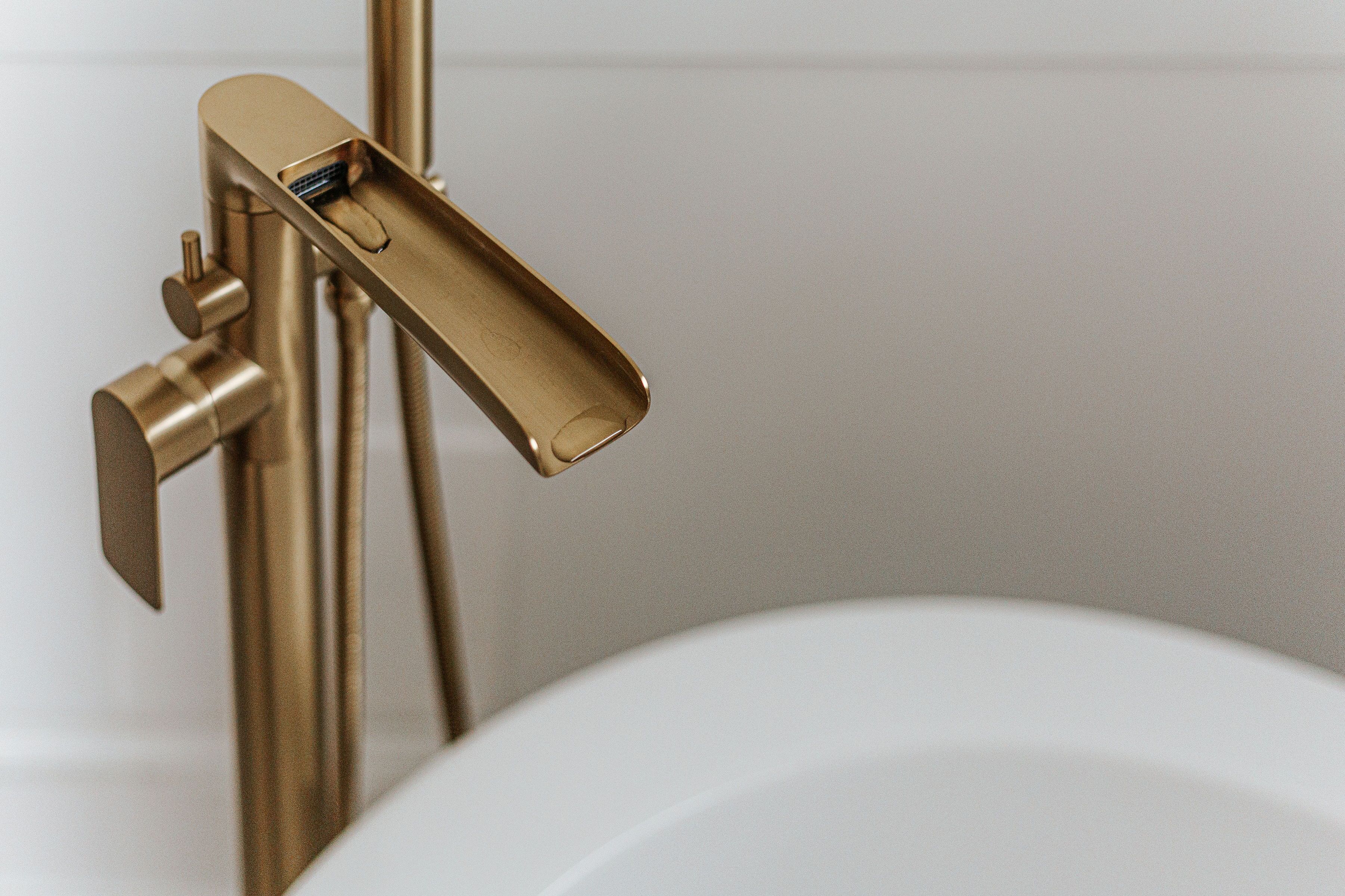 A gold-colored faucet with a lever handle attached to a white sink.