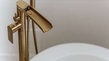 A gold-colored faucet with a lever handle attached to a white sink.