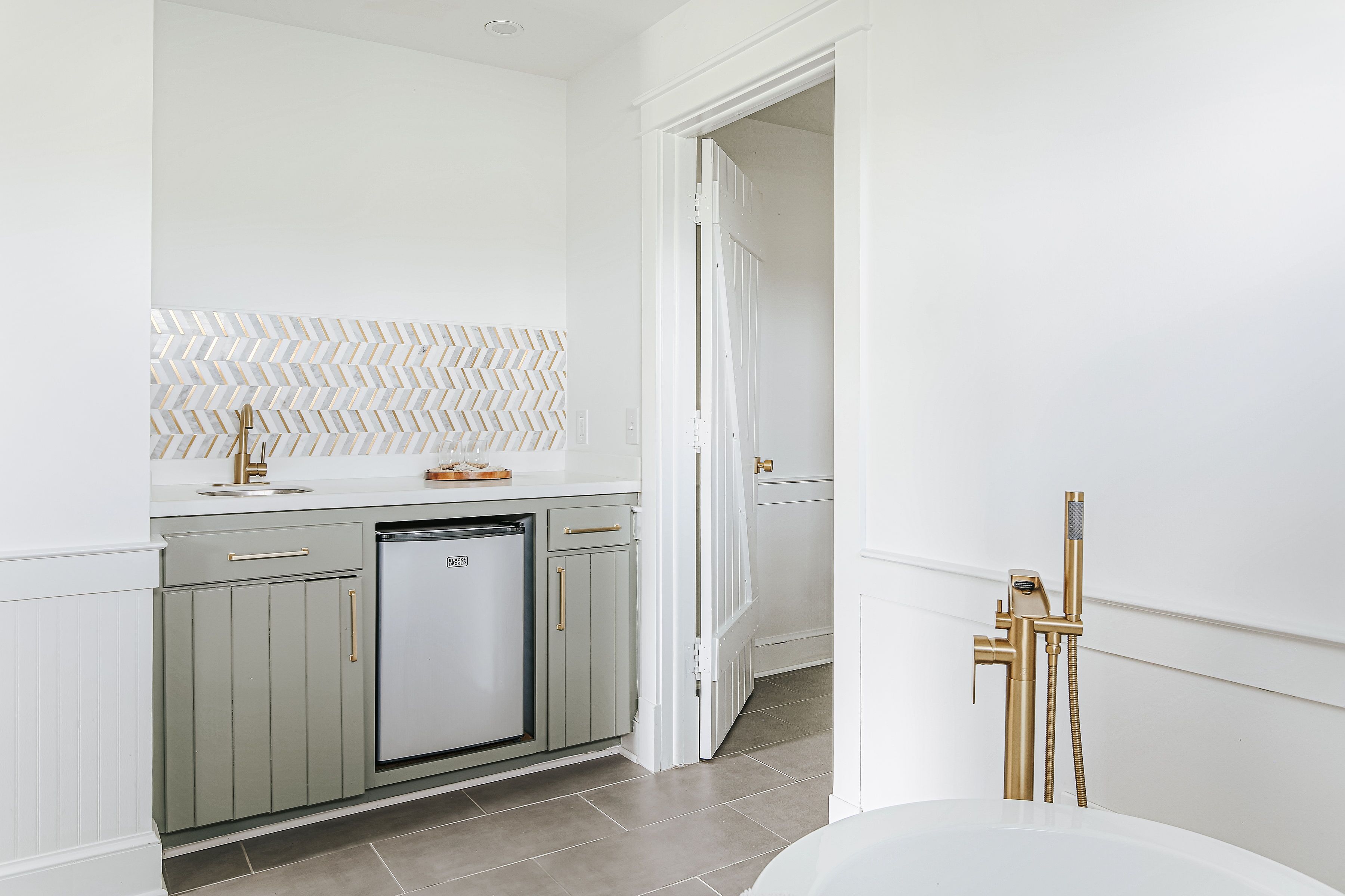 A modern kitchen with a dishwasher, a herringbone-patterned backsplash, and a white countertop.