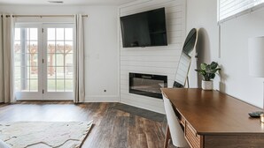 Una sala de estar moderna con chimenea, un televisor montado en la pared y un comedor.