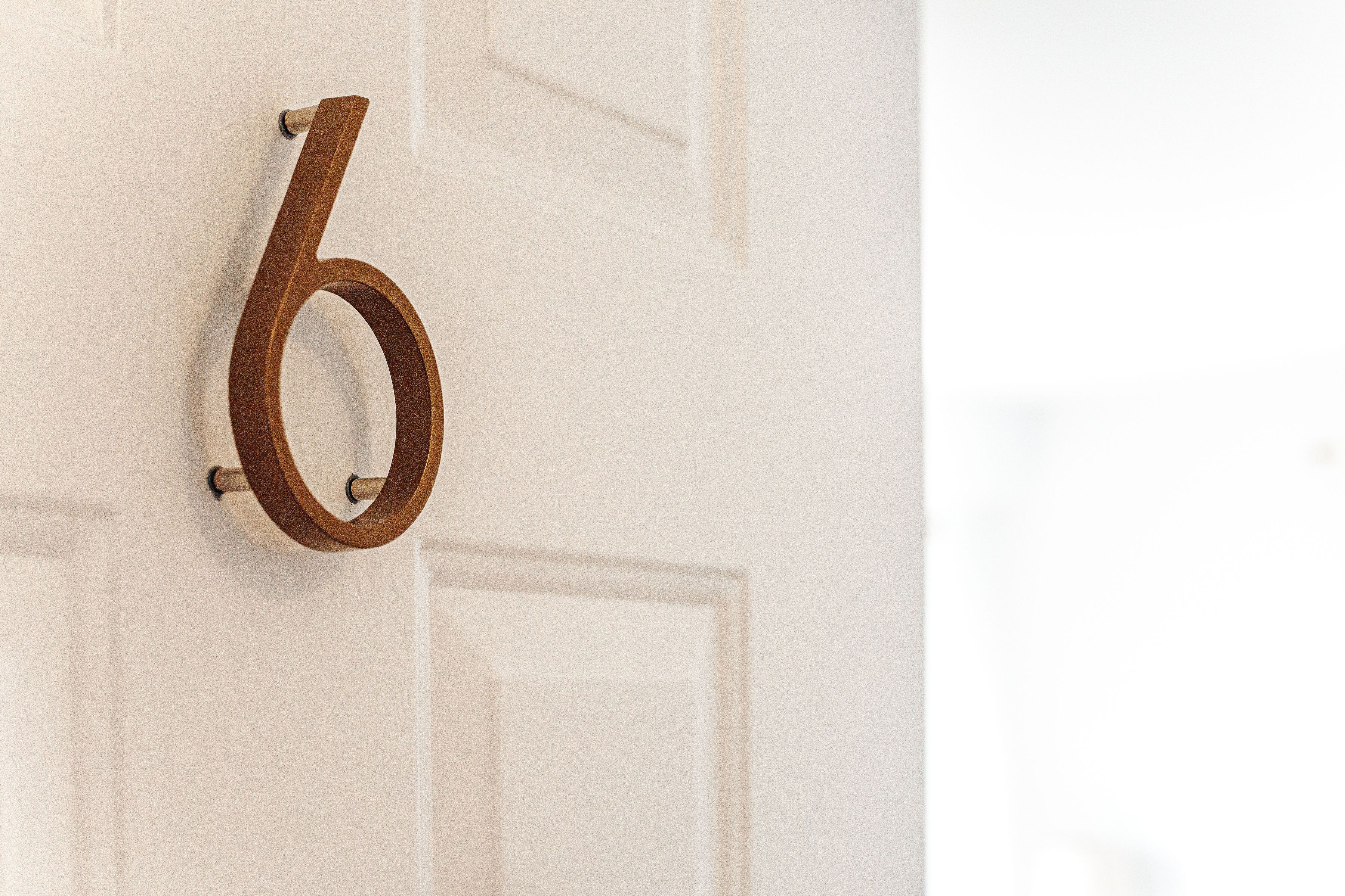 A wooden number '6' sign on a white door.