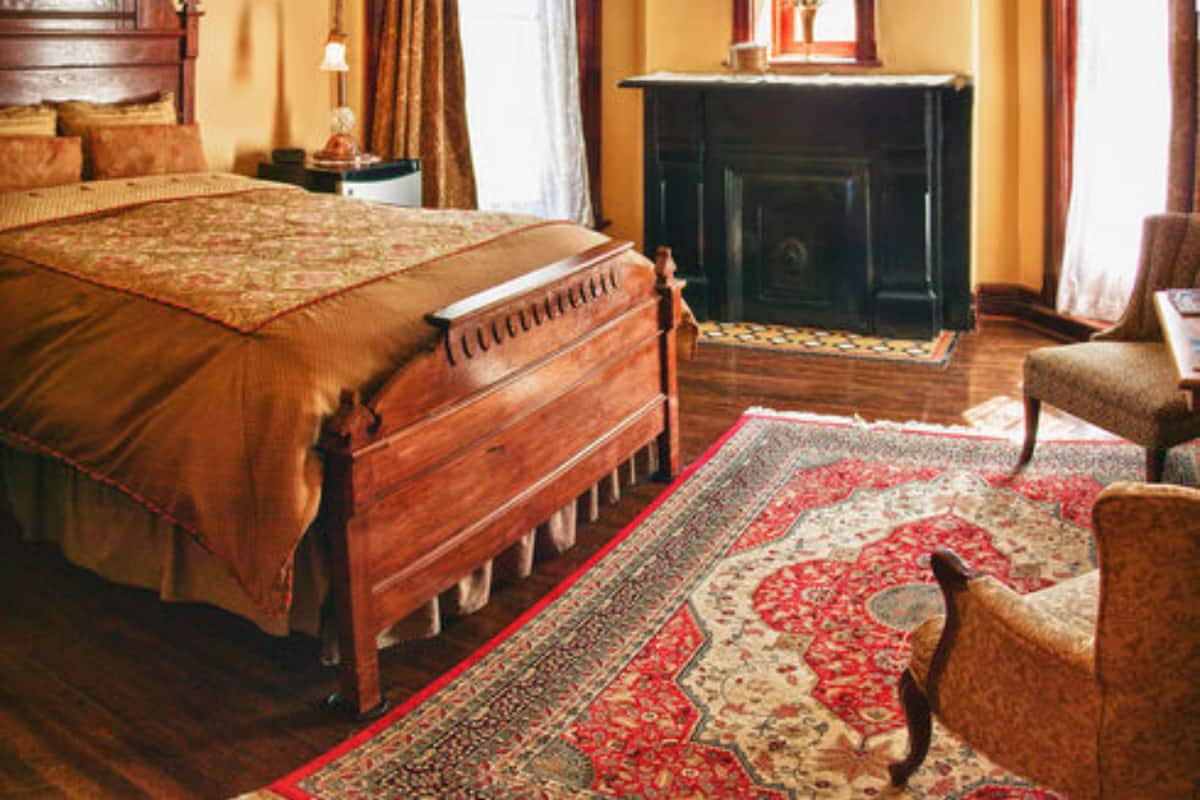 A traditional bedroom with a large bed, a fireplace, and a classic wooden headboard.