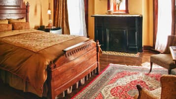 A traditional bedroom with a large bed, a fireplace, and a classic wooden headboard.