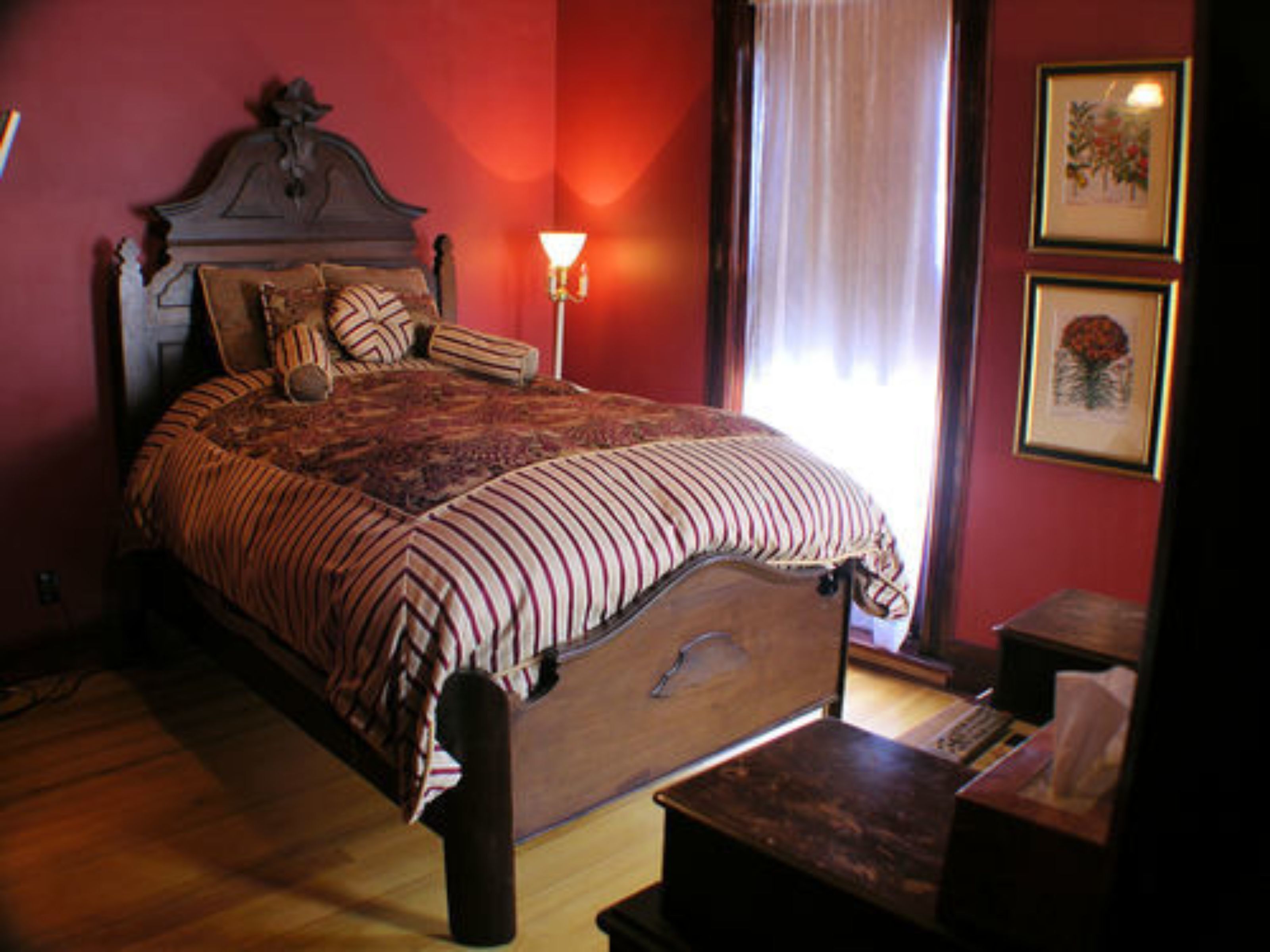 Une chambre avec un grand lit, une table de chevet, une lampe et une fenêtre avec des rideaux.
