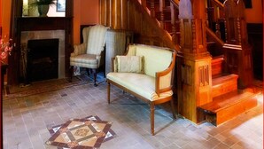 Un interior tradicional con chimenea, una escalera de madera y un suelo estampado.