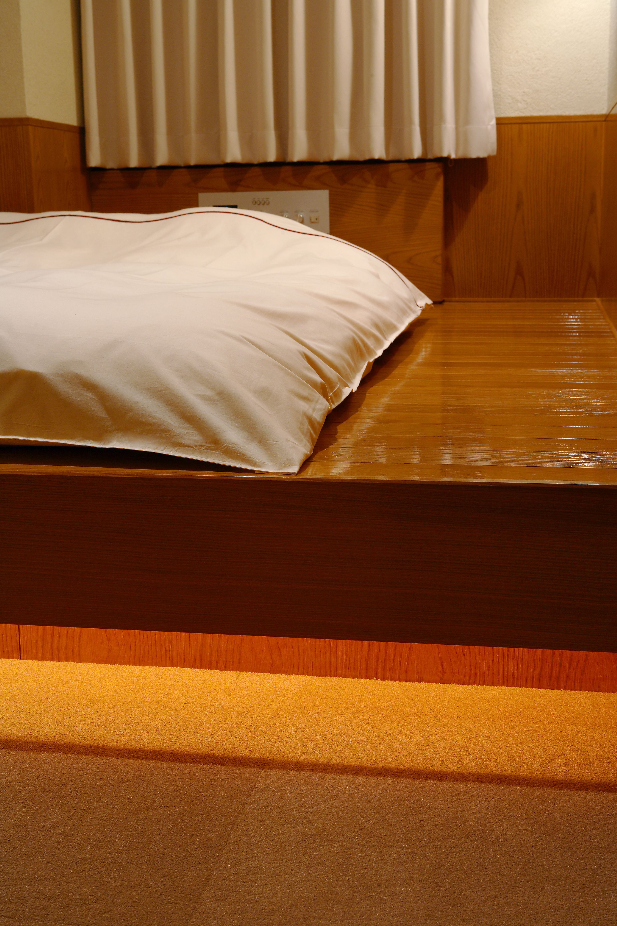A wooden bed with a white pillow and a wooden headboard.