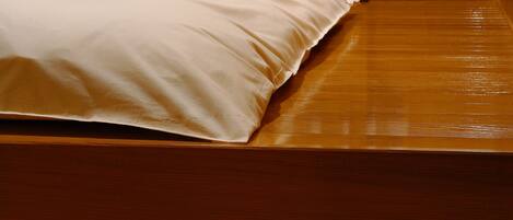 A wooden bed with a white pillow and a wooden headboard.
