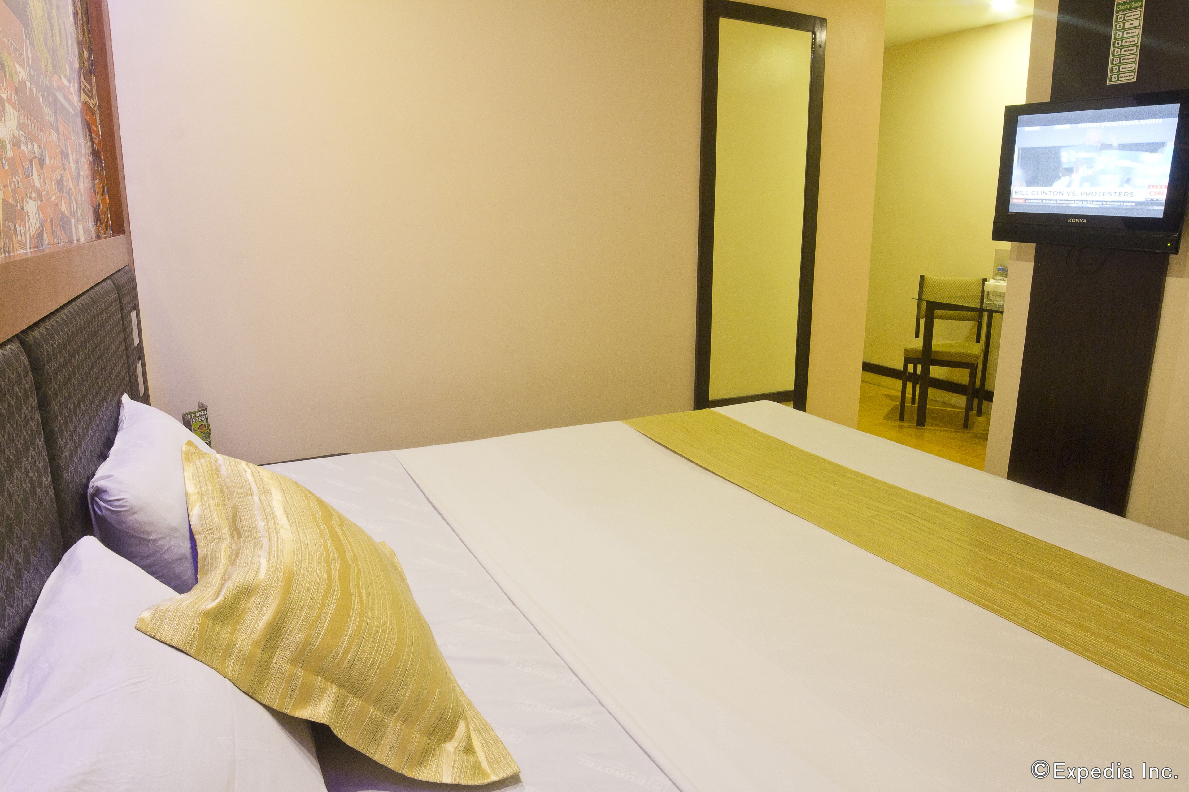A hotel room with a bed, a television mounted on the wall, and a mirror.