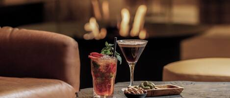 Un cóctel sobre una mesa de madera, con una copa de martini y una bebida adornada con una fresa.