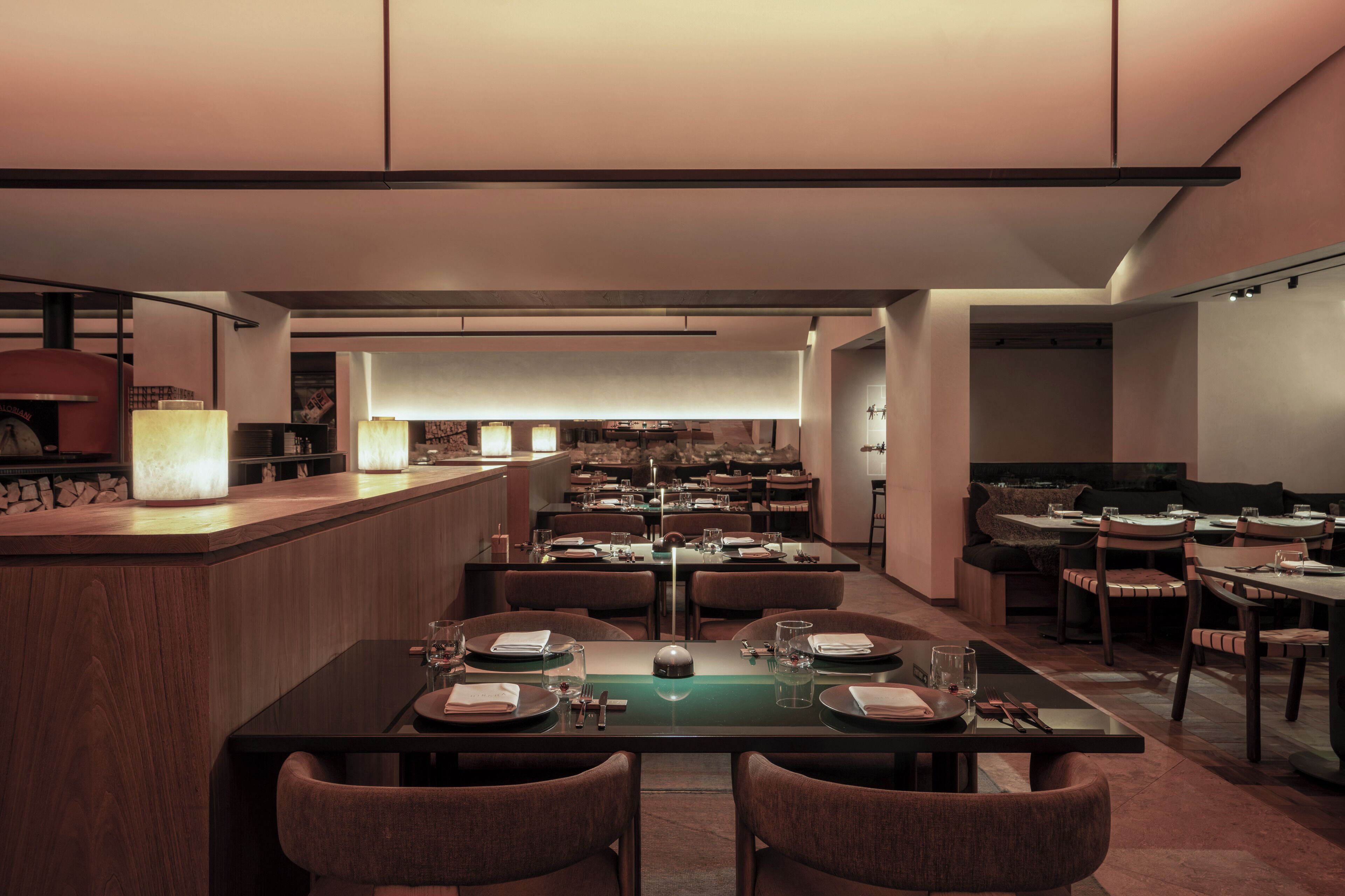 Un restaurante moderno con una barra larga y varias mesas.