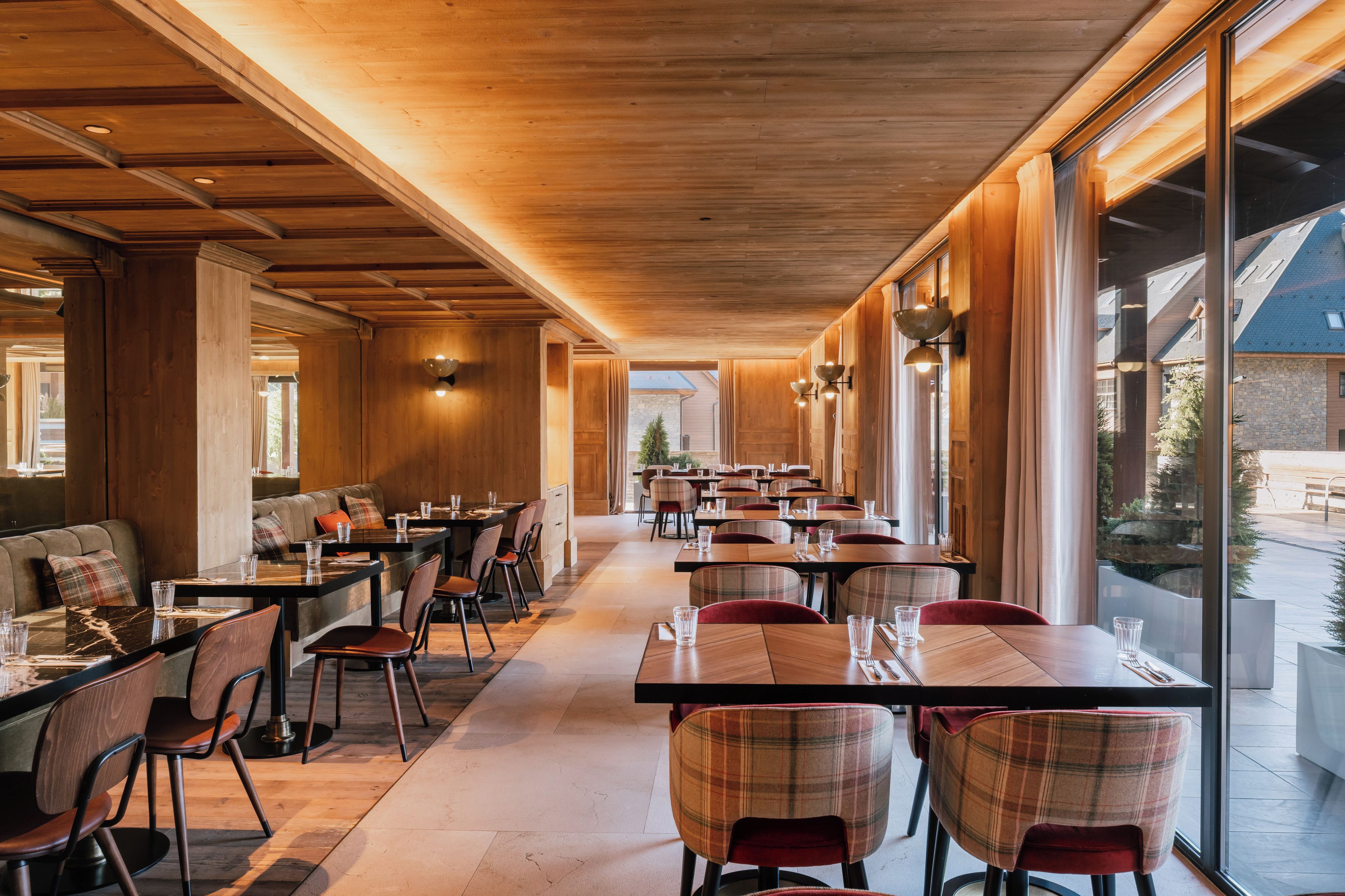 A restaurant with wooden ceiling beams, long tables, and chairs.