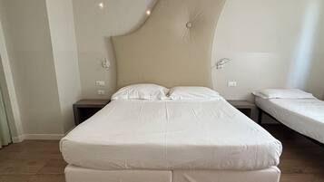 A bedroom with a large bed, two bedside tables, and a wall-mounted air conditioning unit.