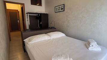 A hotel room with a bed, a desk, a television, and a wall-mounted picture frame.