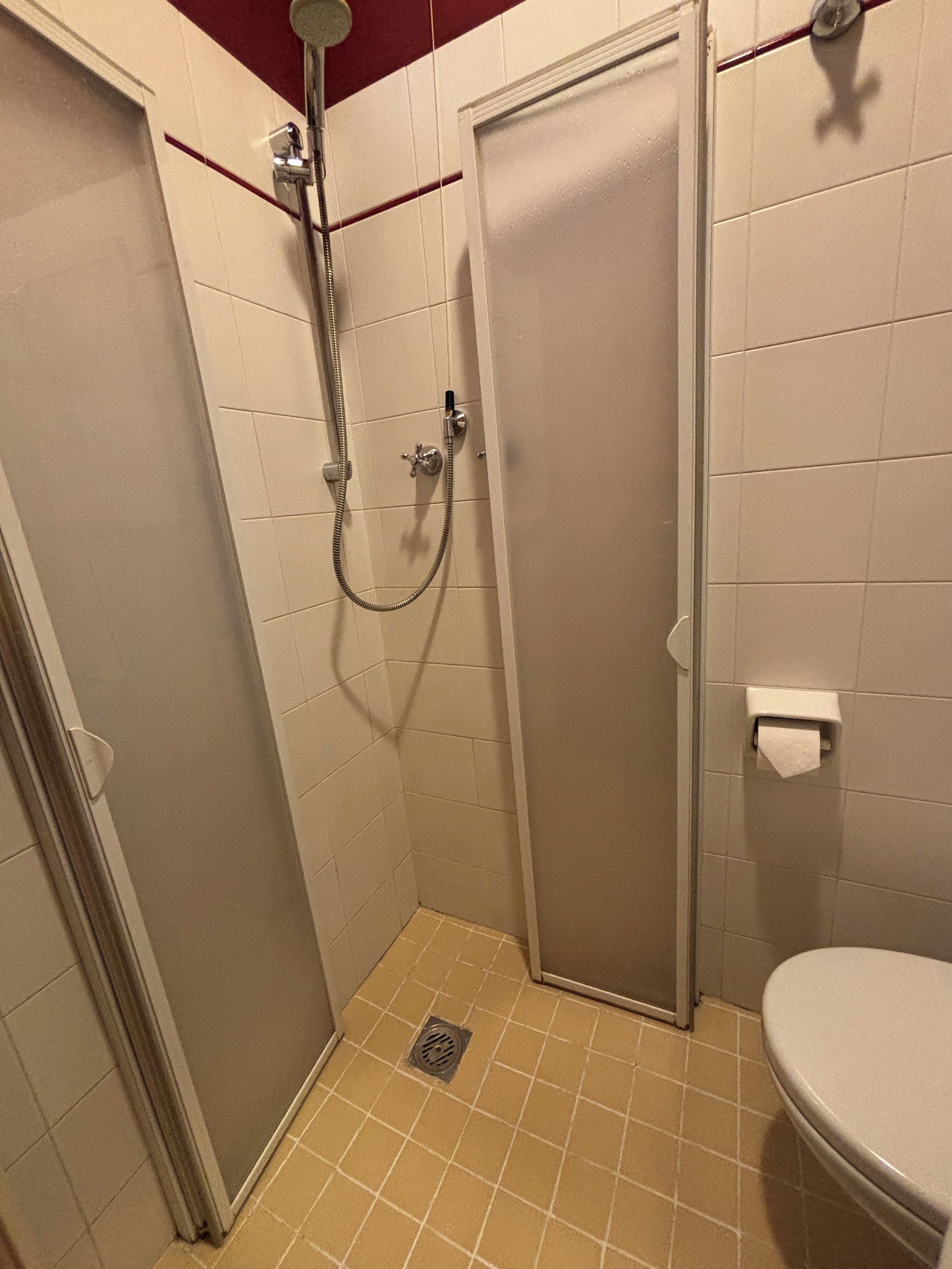Pieni, suljettu suihkutila, jossa on wc ja pyyheannostelija.