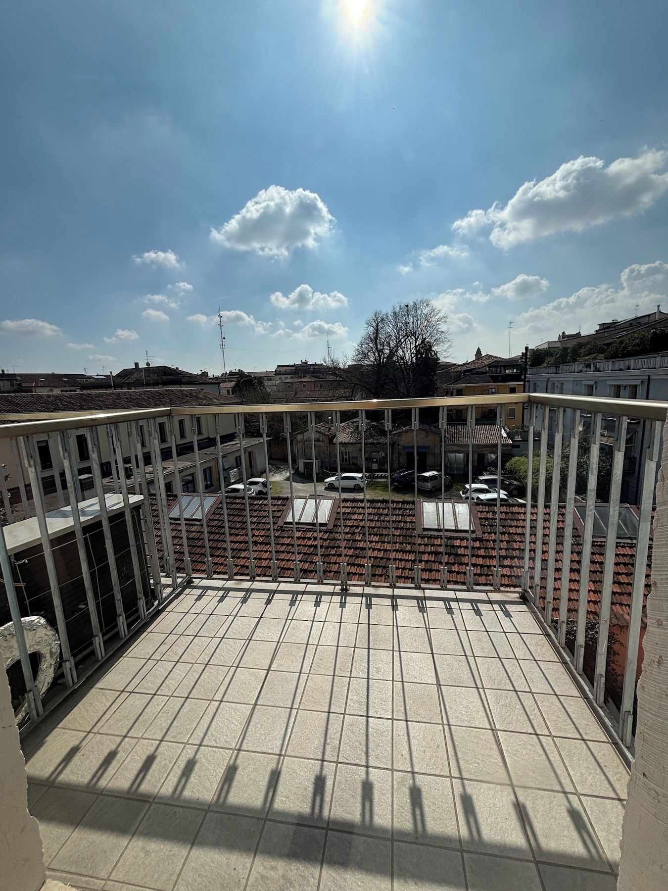 Un balcon donnant sur un parking et des immeubles.