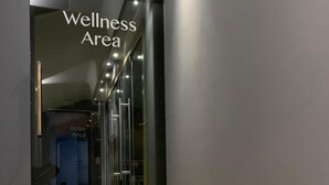 Corredor moderno que dá acesso a uma área de bem-estar, com portas de vidro e chão de madeira.