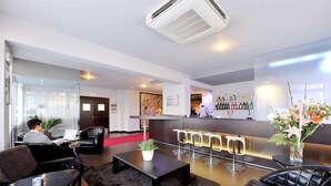 Um saguão de hotel moderno com balcão de recepção, área de estar e bar.