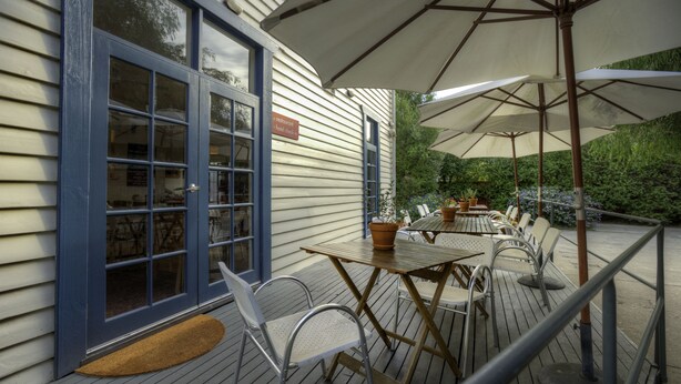 A wooden deck with outdoor tables and chairs, a door with a sign, and a covered area with umbrellas.