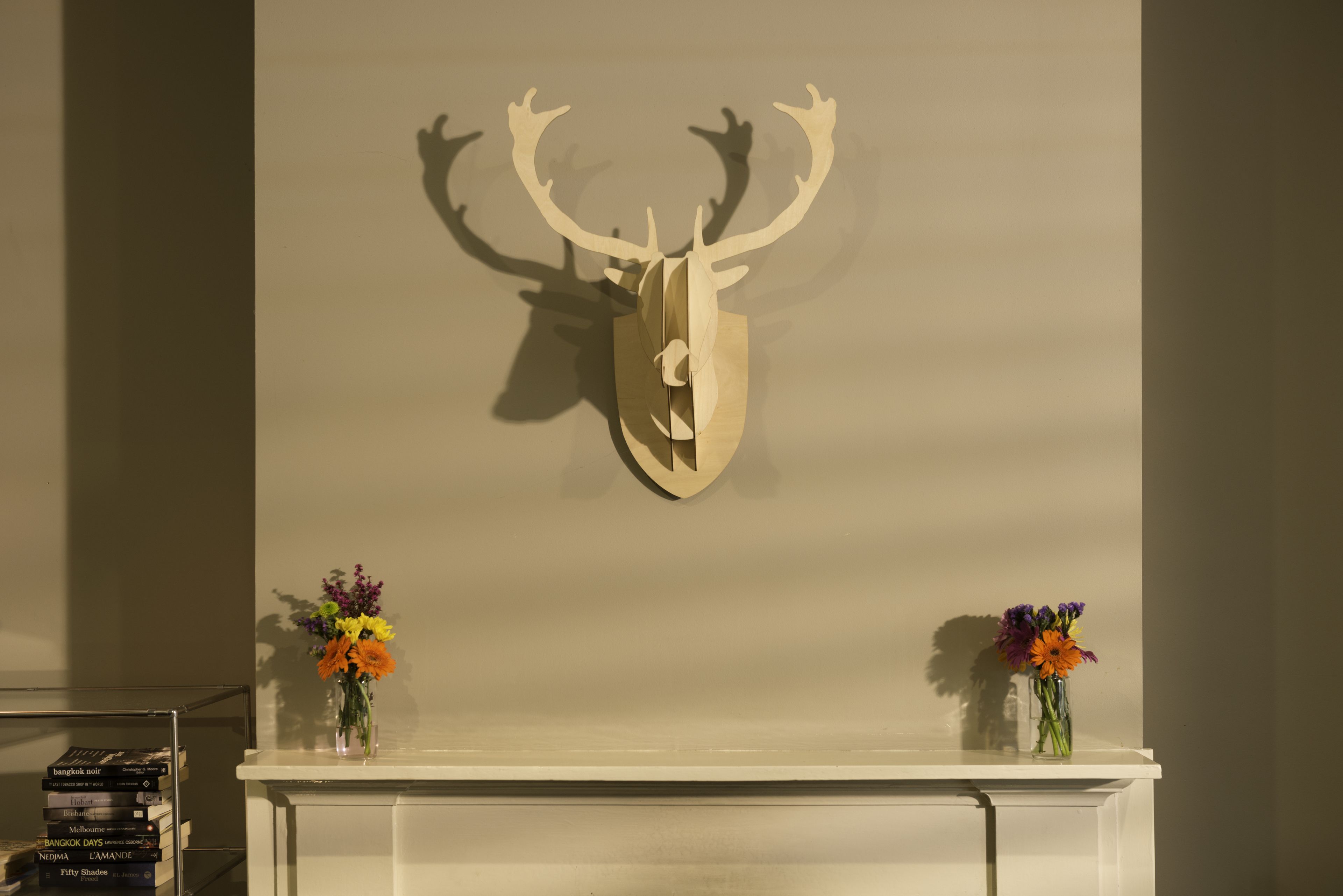 A fireplace with a deer head decoration above it and two vases with flowers on either side.