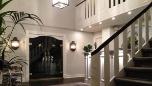 A spacious foyer with a grand staircase, a glass door entrance, and a large potted plant. - Munkebo Kro (Munkebo)