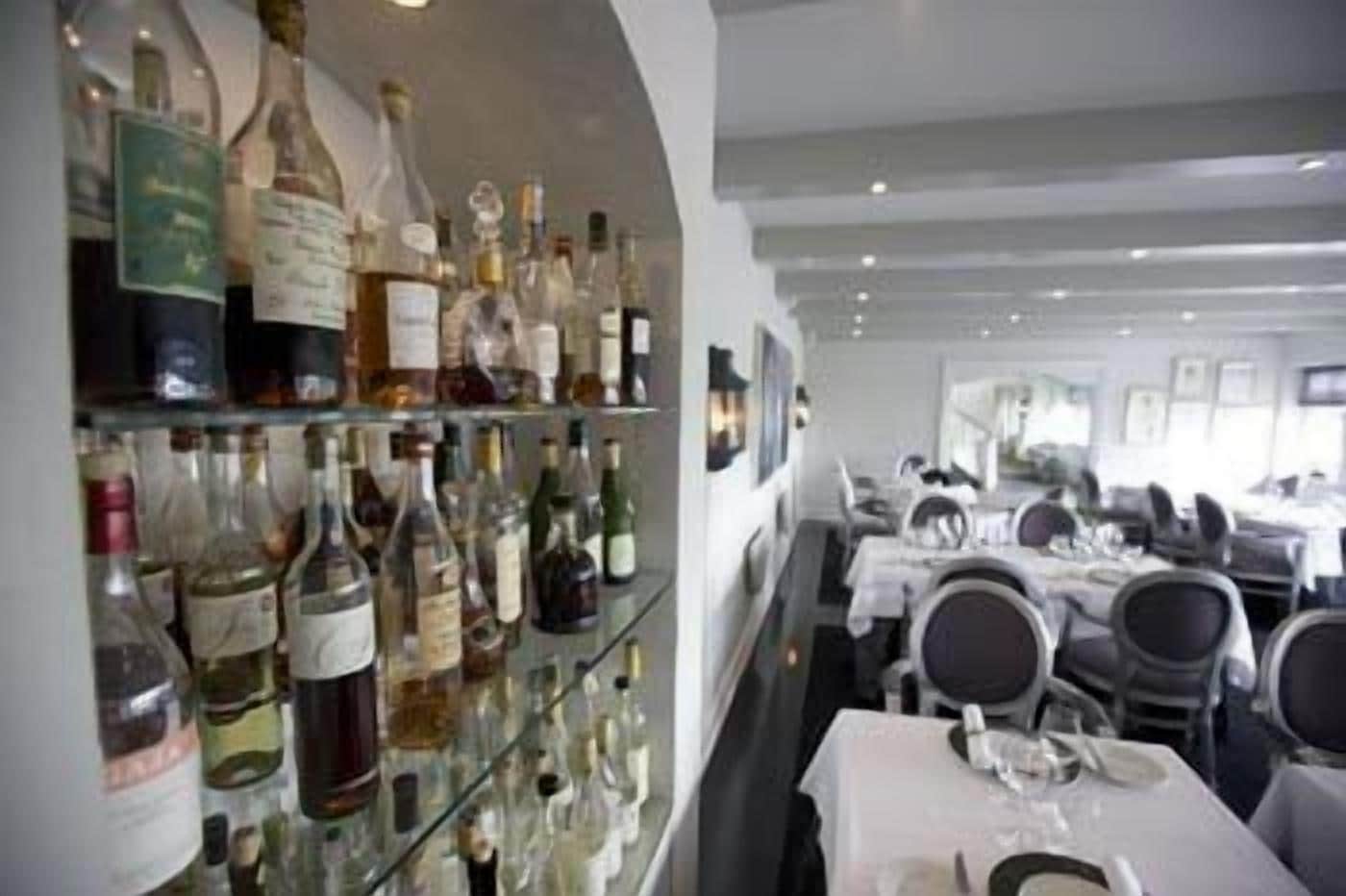 Een restaurant met een wijnrek en gedekte tafels.
